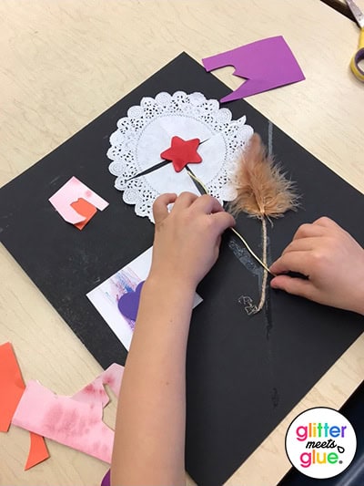 Kindergarten student using foam shapes, features, and doilies for a collage.