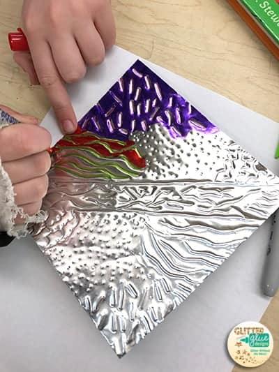 Students drawing on metal embossing using permanent markers.