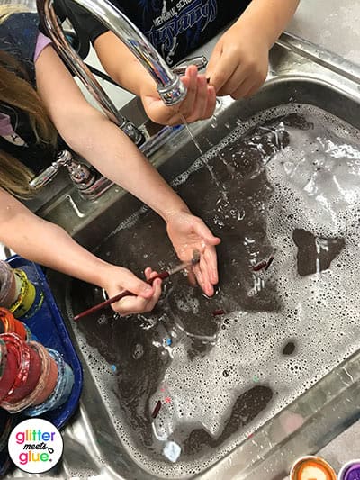 kids cleaning paintbrushes in the art room